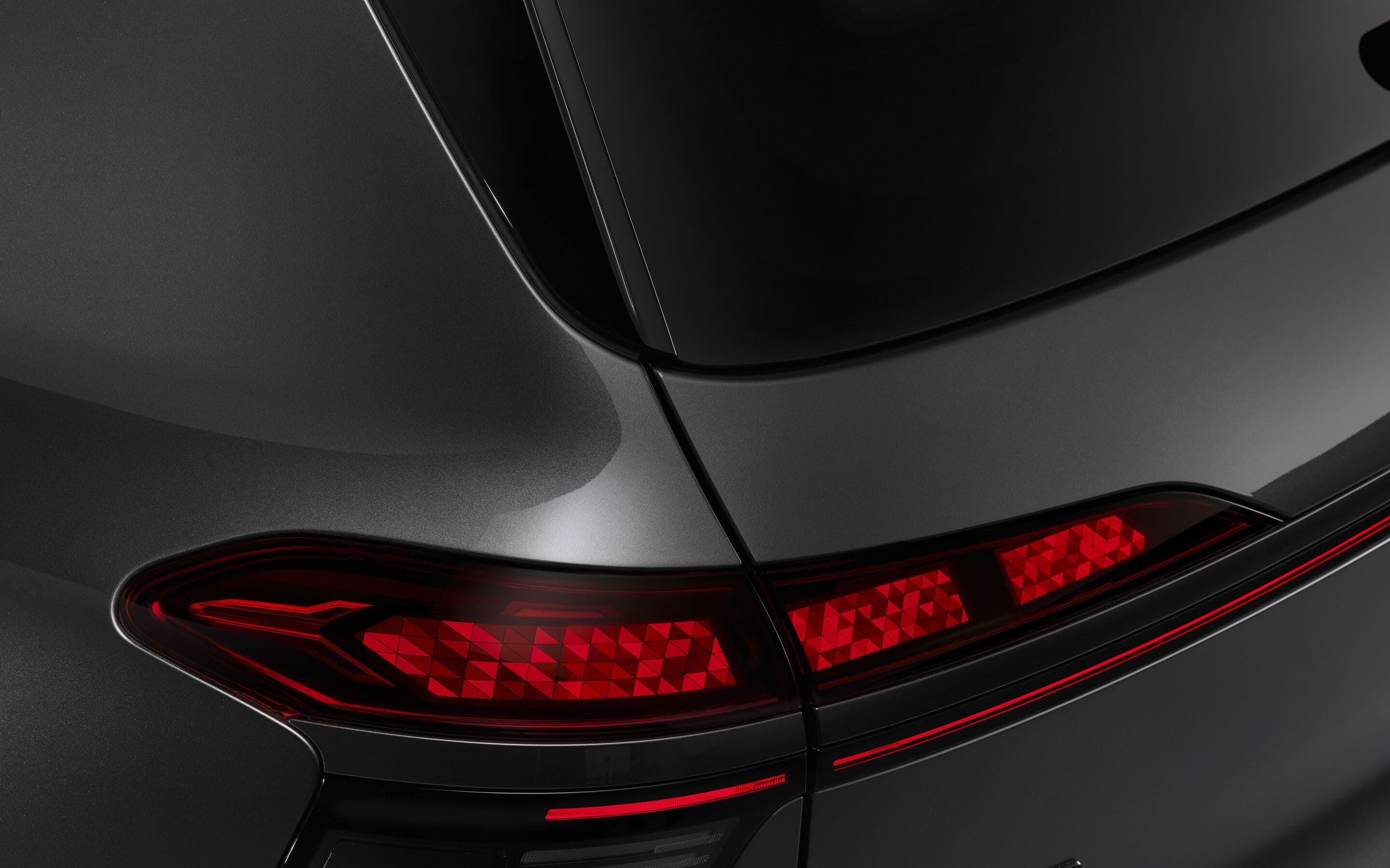 Rear of an Audi Q9 showing curved digital OLED rear-light panels with segmented light signatures